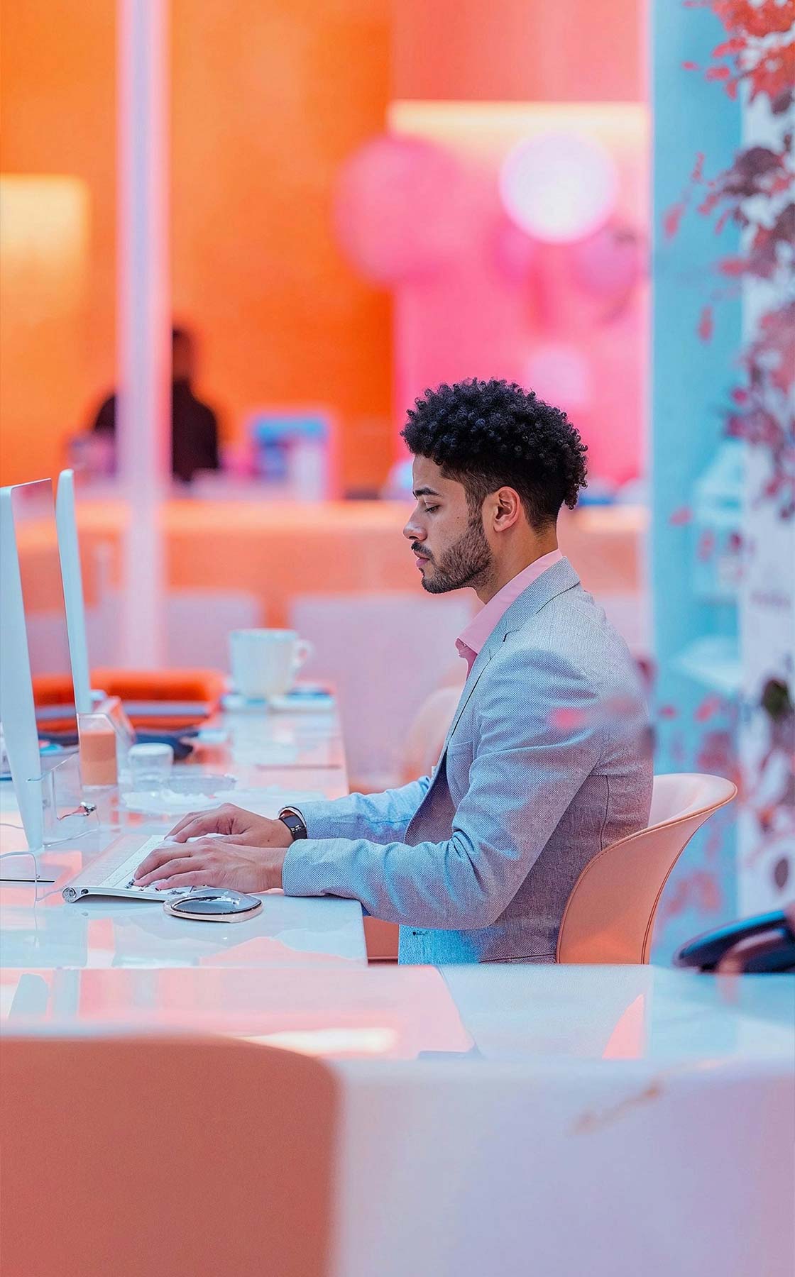 A man in a gray jacket works on a computer
