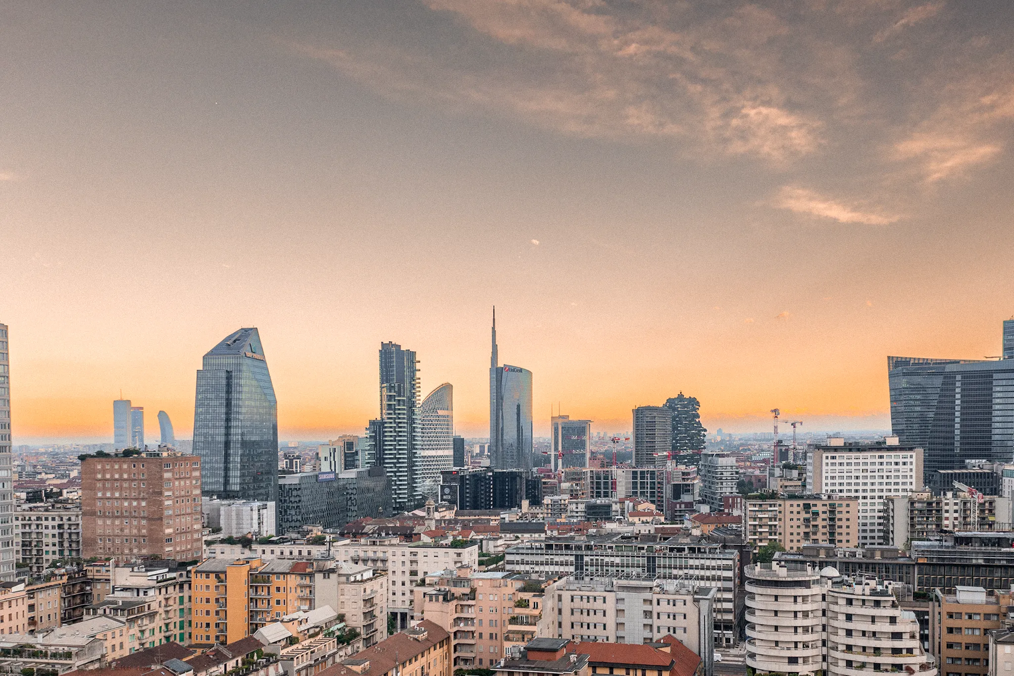 Panorama di Milano con grattacieli moderni come la Torre Unicredit sotto un cielo all'imbrunire.