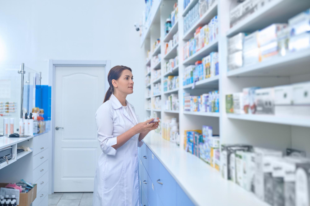 farmaceutka v lekárni pozerá na policu s liekmi