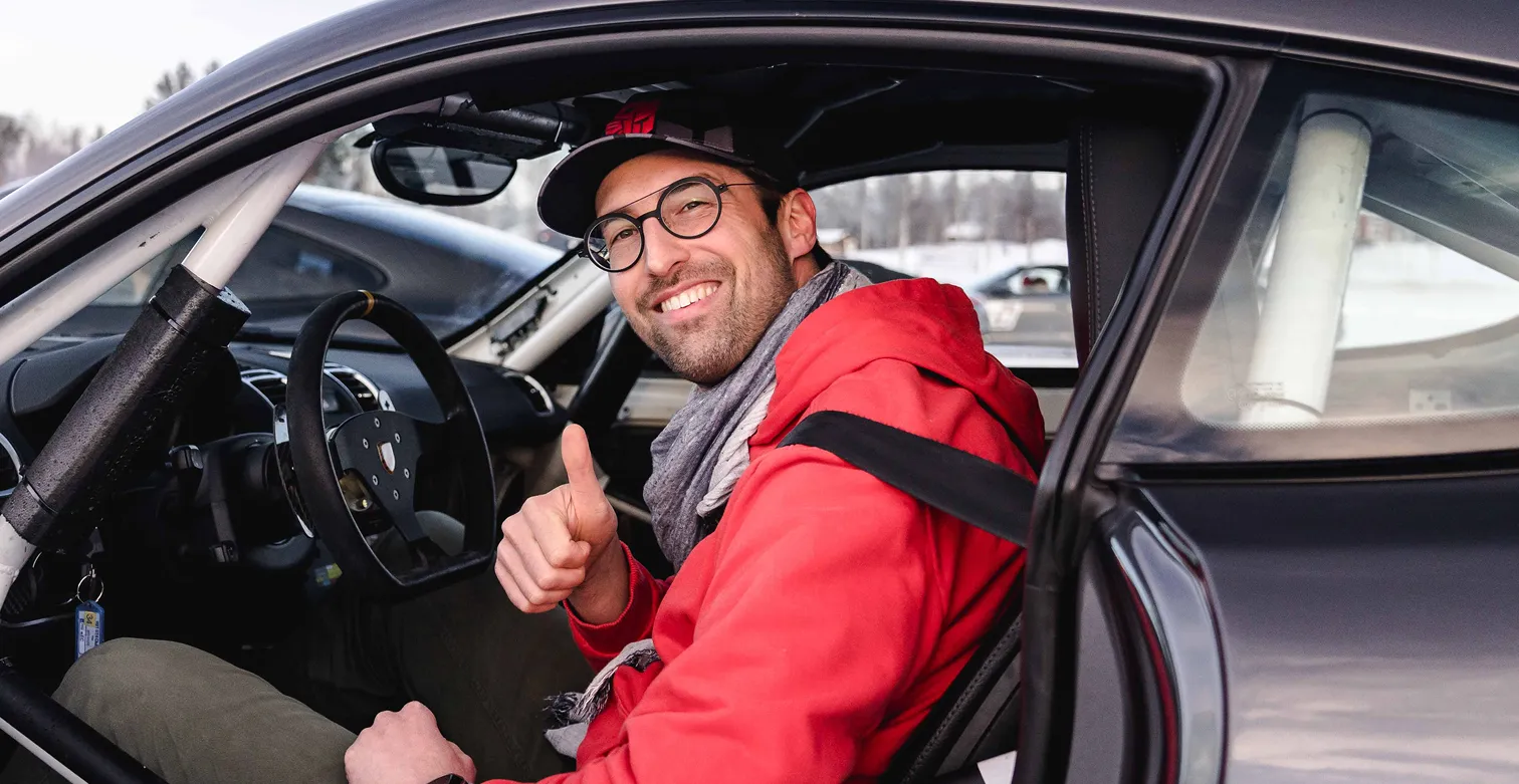 Ein begeisterter Teilnehmer des ESC European Speed Club gibt im Cockpit eines Rennwagens den Daumen hoch beim Icedriving in Schweden.

