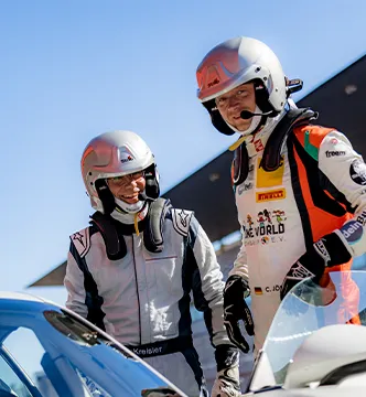 Zwei Rennfahrer des ESC European Speed Club in voller Montur im Gespräch neben ihrem Fahrzeug in der Boxengasse.

