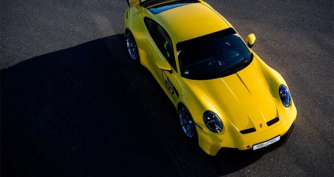 Luftaufnahme eines gelben Porsche 911 GT3 vom ESC European Speed Club auf einer kurvigen Rennstrecke.

