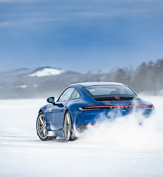 Blauer Porsche 911 des European Speed Club driftet beim Icedriving-Event in Schweden durch den Schnee.

