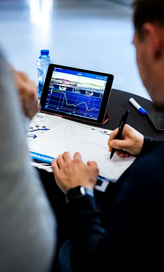Professionelles Coaching beim ESC: Ein Instruktor analysiert Telemetriedaten auf einem Tablet und macht Notizen zur Rundenoptimierung.

