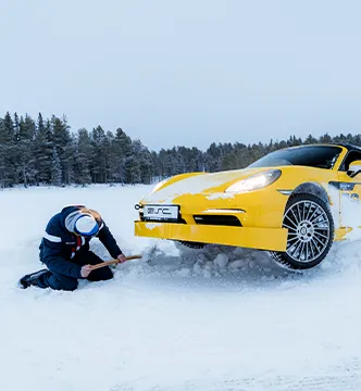 Ein Teilnehmer des ESC Icedriving-Events schaufelt seinen gelben Porsche aus dem Tiefschnee frei.

