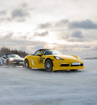 Zwei Porsche Boxster des ESC European Speed Club, angeführt von einem gelben Modell, bei einer Fahrübung auf Eis in Schweden.