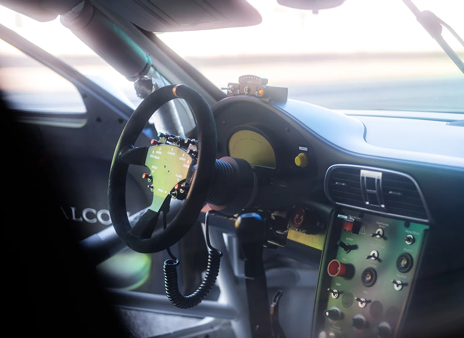 Detailaufnahme des Rennwagen-Cockpits eines ESC European Speed Club Fahrzeugs mit Rennlenkrad, Schaltern und Rollkäfig.

