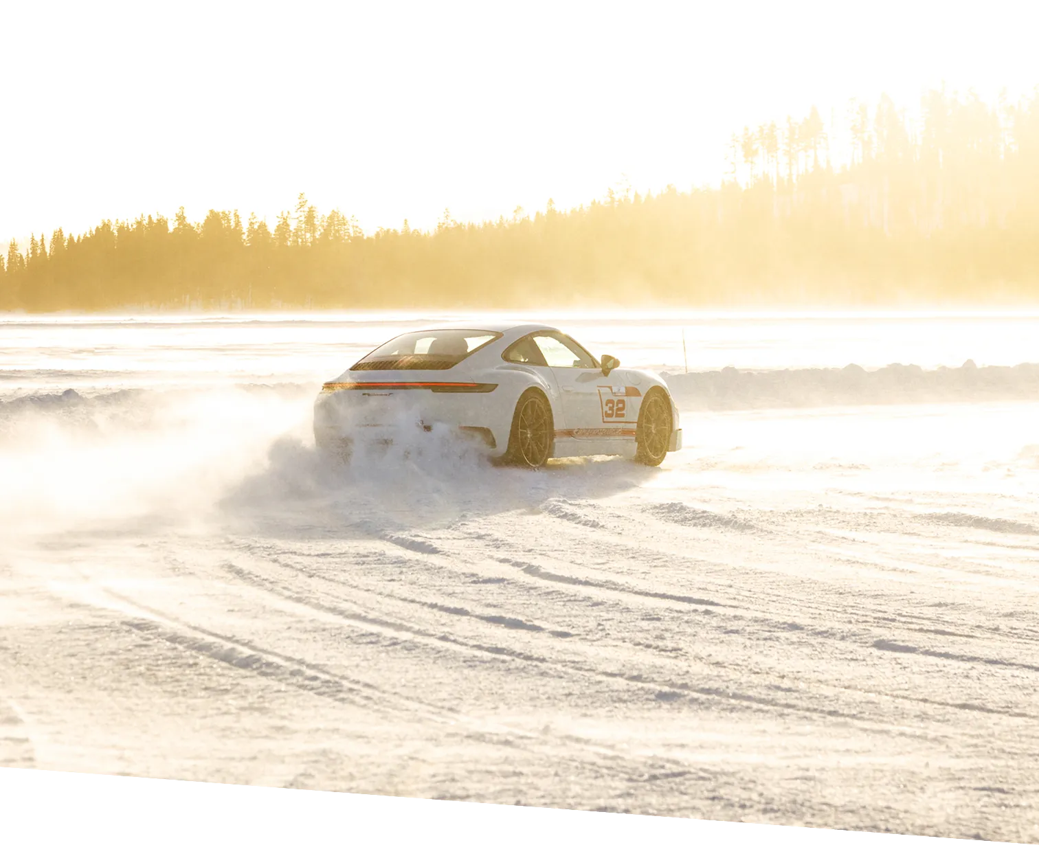 Silberner Sportwagen mit der Nummer 32, der auf einer schneebedeckten Straße bei Sonnenschein driftet.