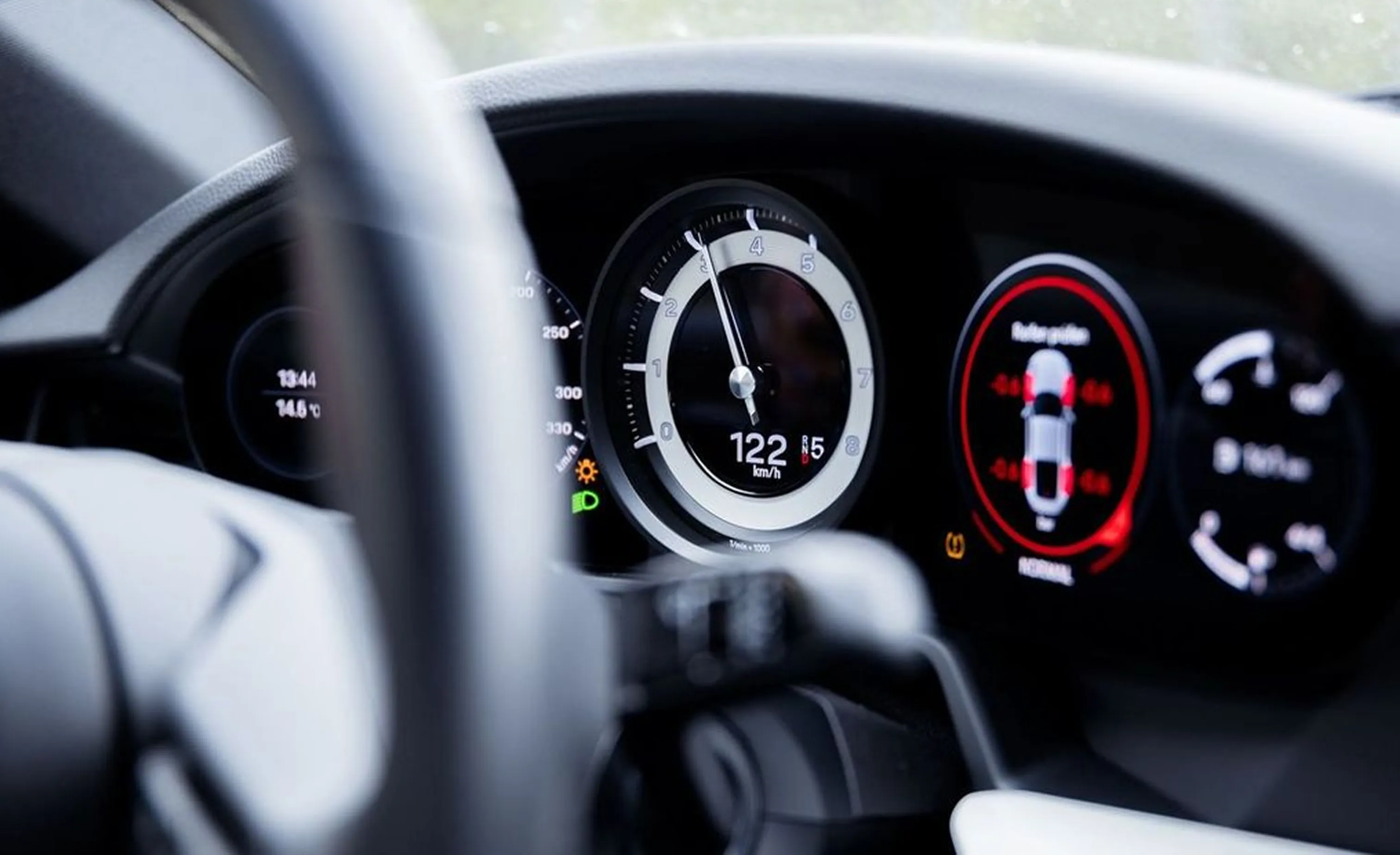 Armaturenbrett eines Autos mit Tachoanzeige bei 122 km/h und digitalen Anzeigen für Uhrzeit, Außentemperatur und Fahrzeugstatus.