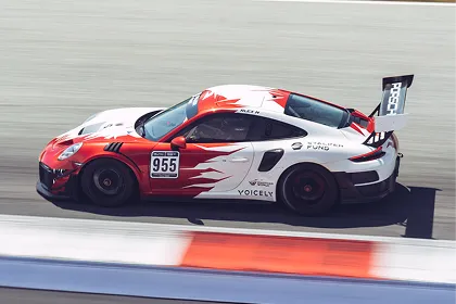 Weißer und roter Rennwagen mit der Nummer 955 fährt auf einer Rennstrecke.