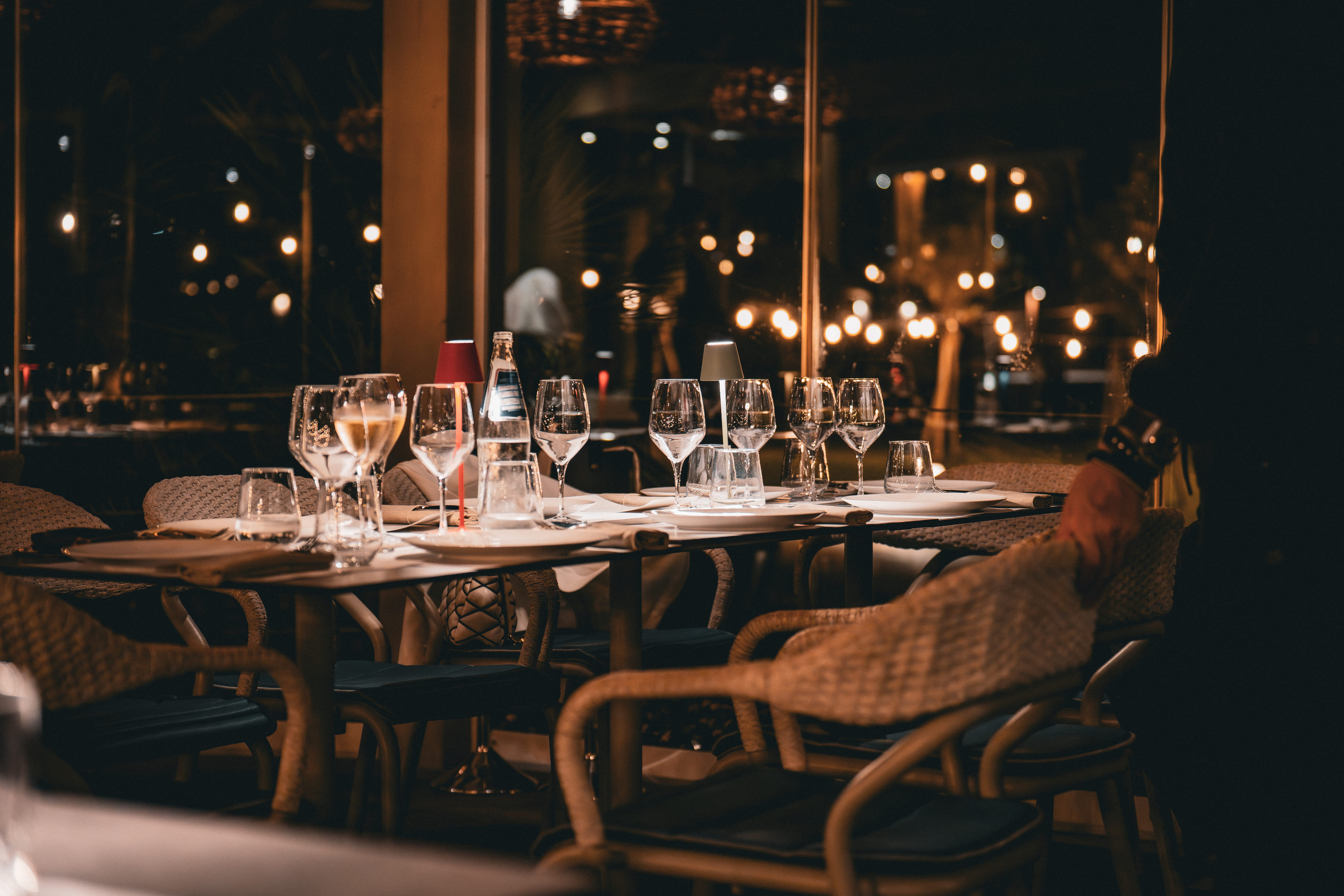Abendessen im Restaurant mit einem gedeckten Tisch, Weingläsern und gedämpfter Beleuchtung im Hintergrund.