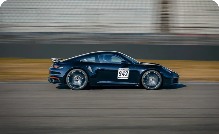 Schwarzer Rennsportwagen mit der Startnummer 942 fährt mit hoher Geschwindigkeit auf einer Rennstrecke.