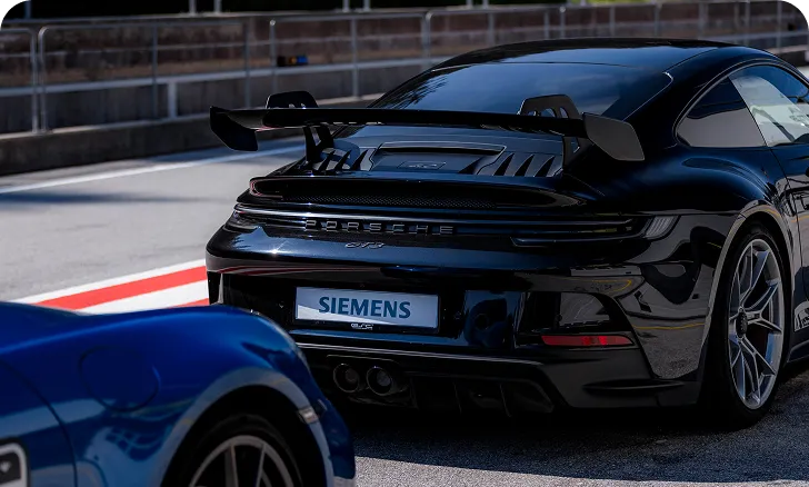 Heckansicht eines schwarzen Porsche-Sportwagens auf einer Rennstrecke mit Siemens-Kennzeichen.