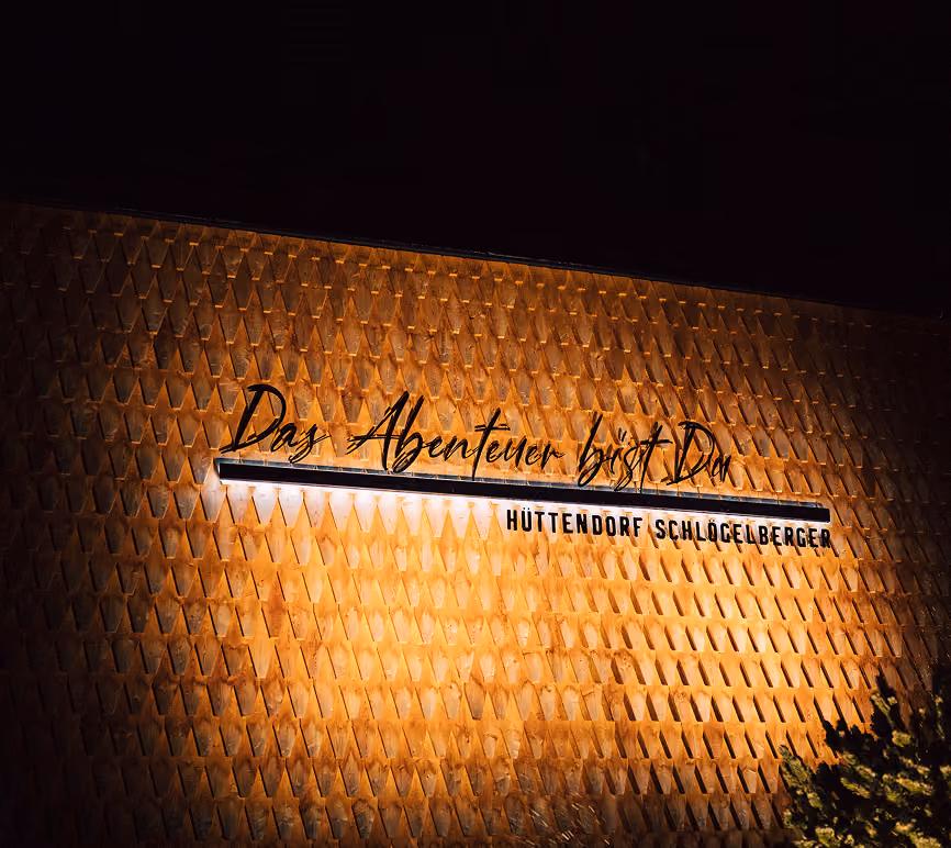 Illuminated wall with the inscription Das Abenteuer bist Du, Hüttendorf Schlösslberger.