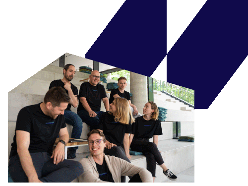 Seven casually dressed people sitting and chatting on wide concrete steps inside a building with large windows.