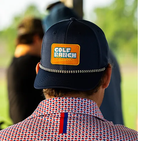 Rear view of a person wearing a navy Golf Ranch Classic cap and a patterned shirt at a golf range.
