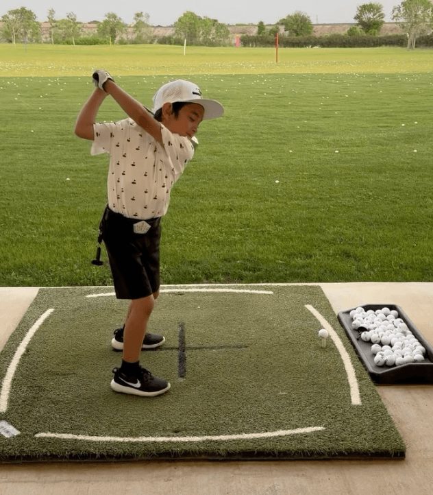 Young golfer finishing a swing on the Golf Ranch range