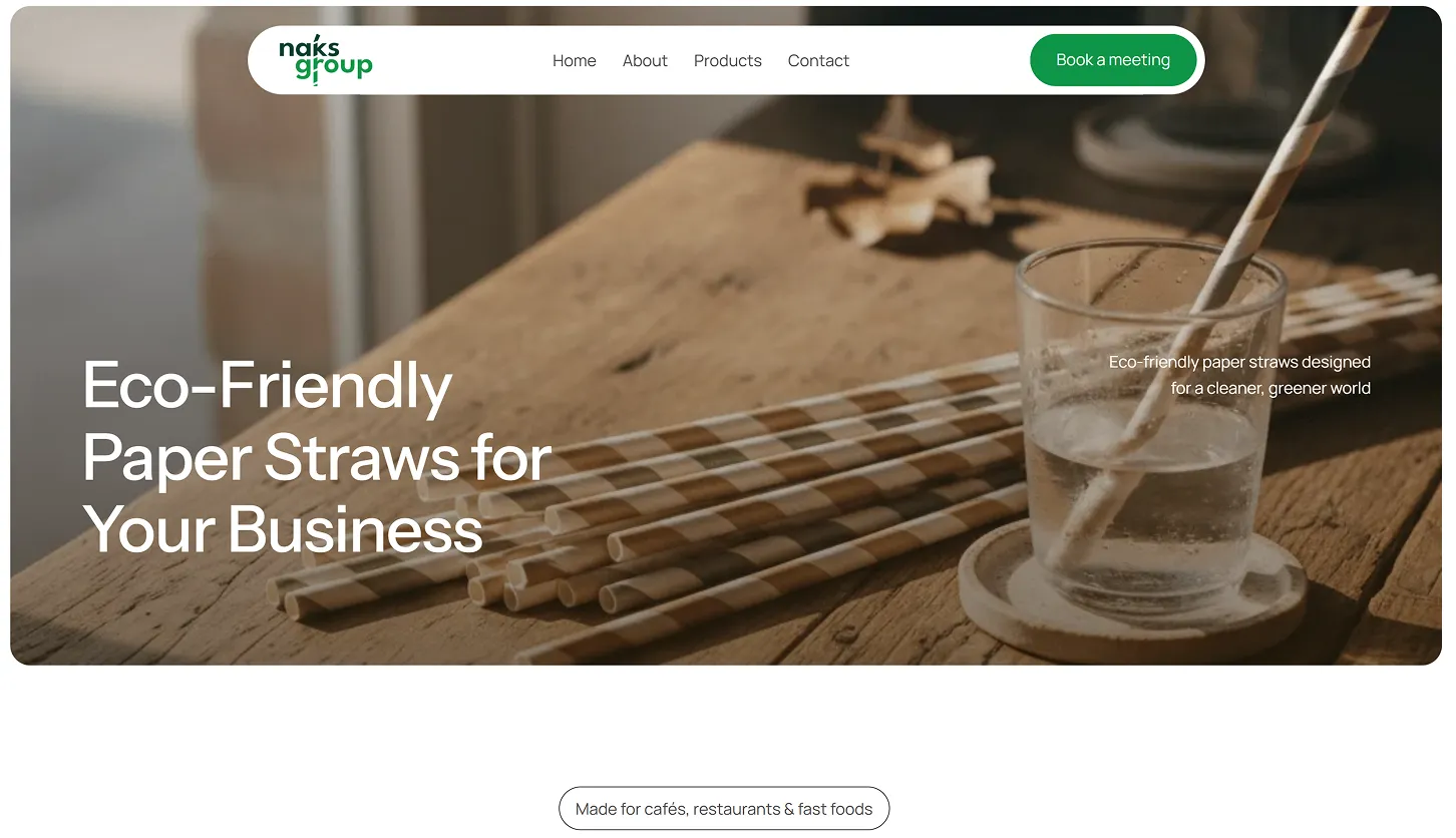 Eco-friendly striped paper straws laid on a wooden surface next to a glass of water with a paper straw.