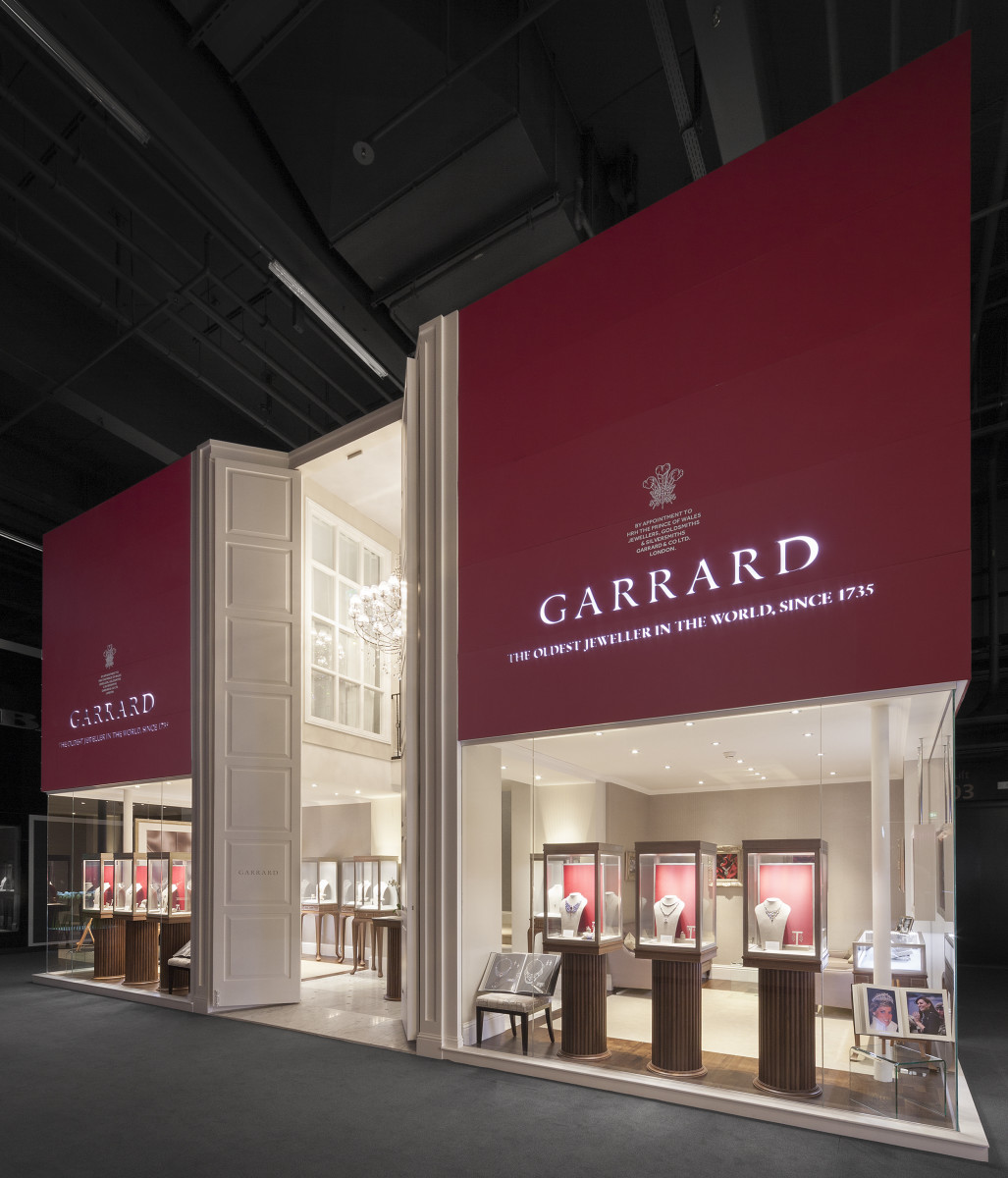 The Garrard trade booth, a white and oxblood pavilion with lit vitrines and the brand wordmark above.