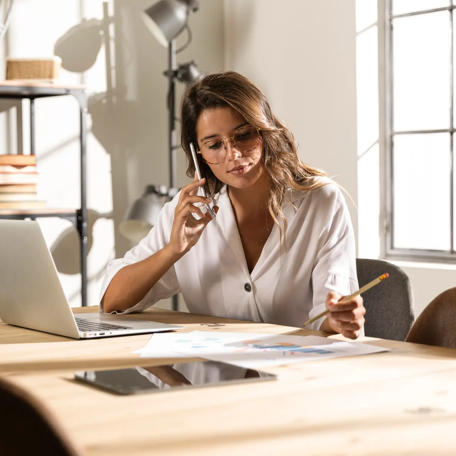 Woman on a phone call at her desk reviewing documents, symbolizing the initial discovery call with the Talent On Demand team.