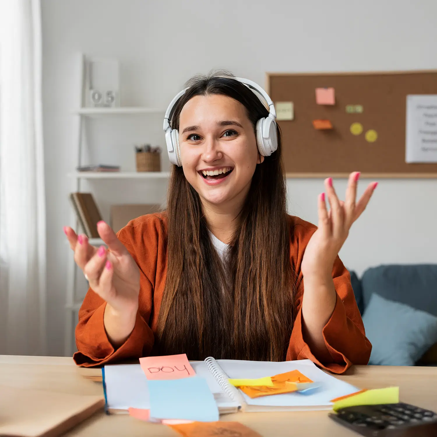 Young woman wearing white headphones smiling and gesturing during a remote video call.