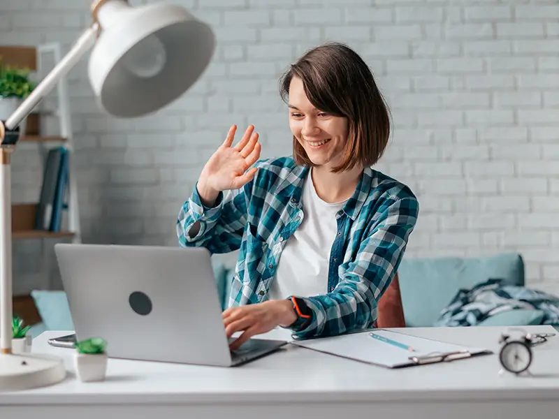 Remote professional waving during video call, demonstrating seamless global team collaboration