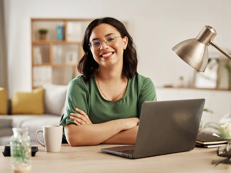 Confident remote worker smiling at desk with laptop, representing global talent opportunities