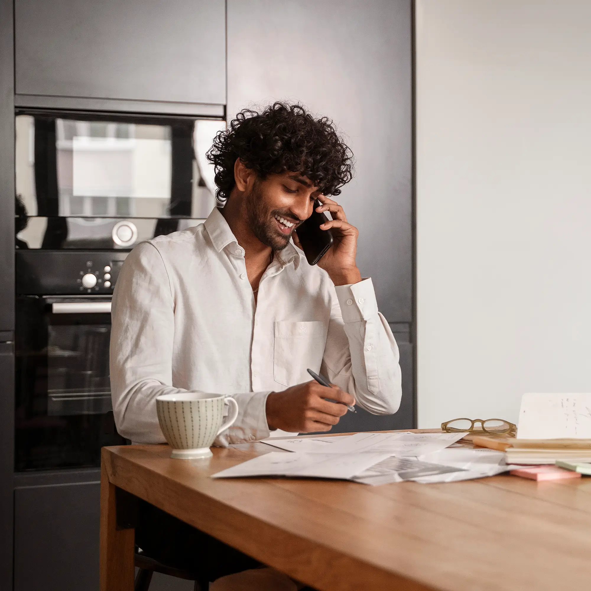 Professional remote marketer taking client call while reviewing campaign reports from modern home office.