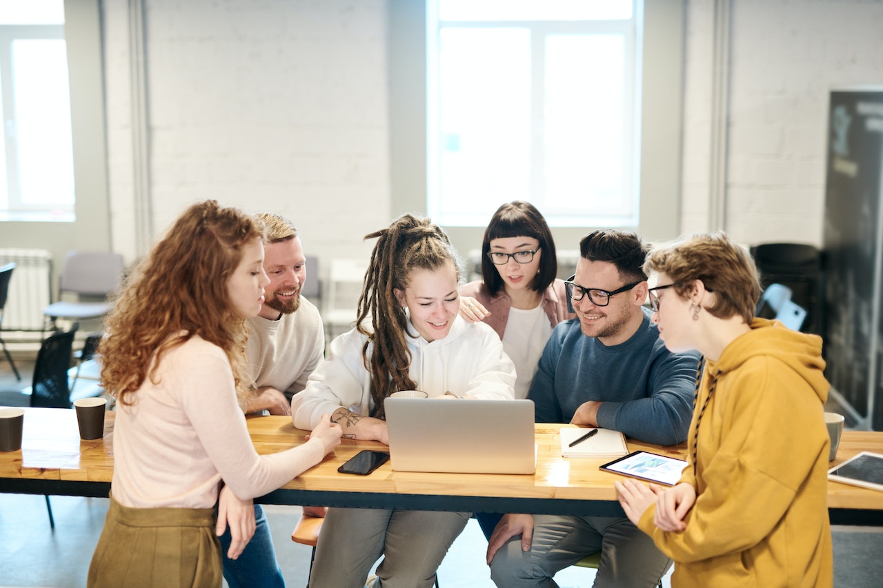 A happy team gathers around a laptop