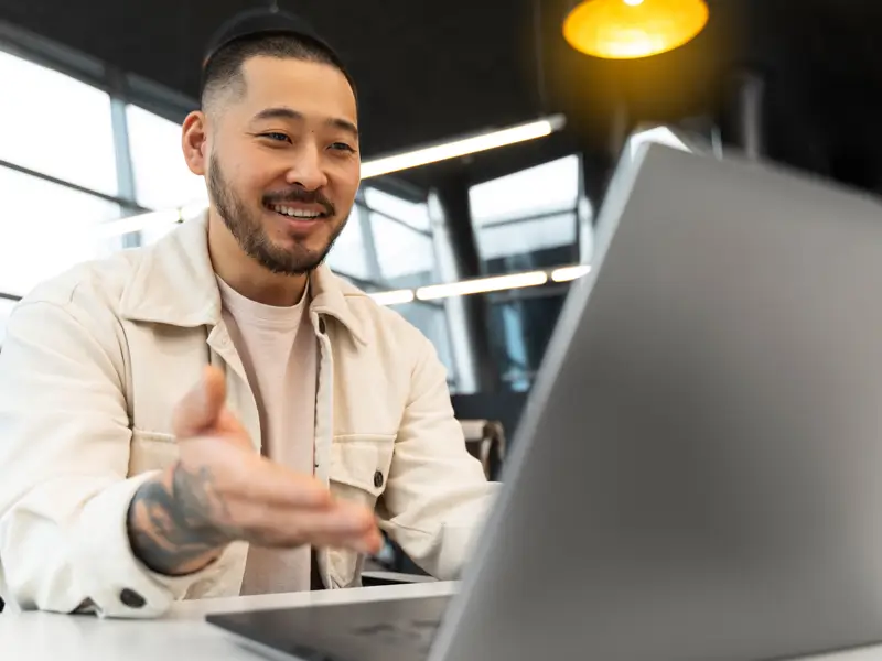 Smiling Asian businessman in video conference representing Somewhere's diverse global B2B sales talent network for US companies