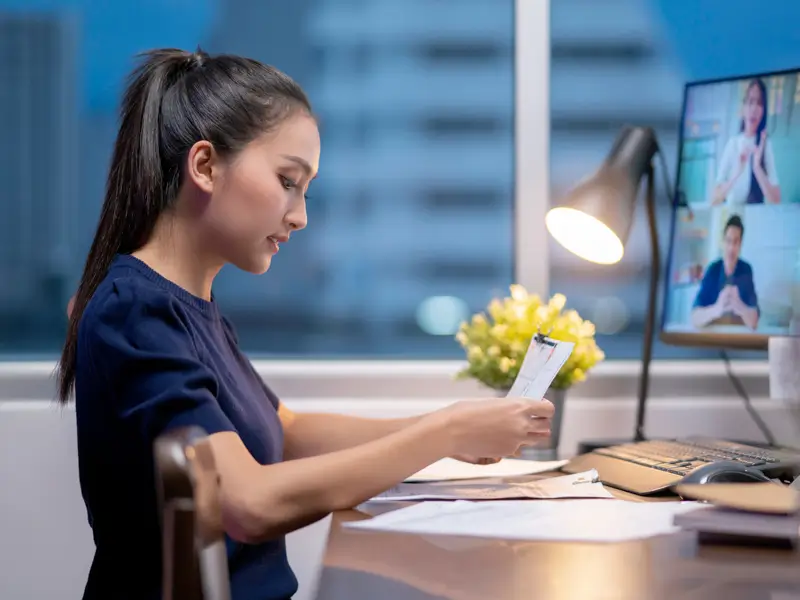 Professional remote worker reviewing documents during video conference with global team members