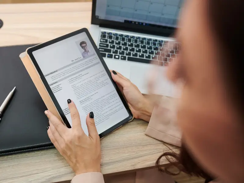 Professional hiring manager examining digital resume on tablet during candidate screening and selection process