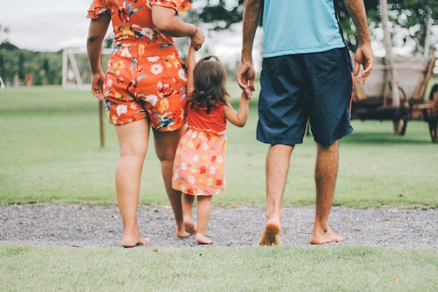 Filipino family walking barefoot in a park, holding hands and spending quality time together outside
