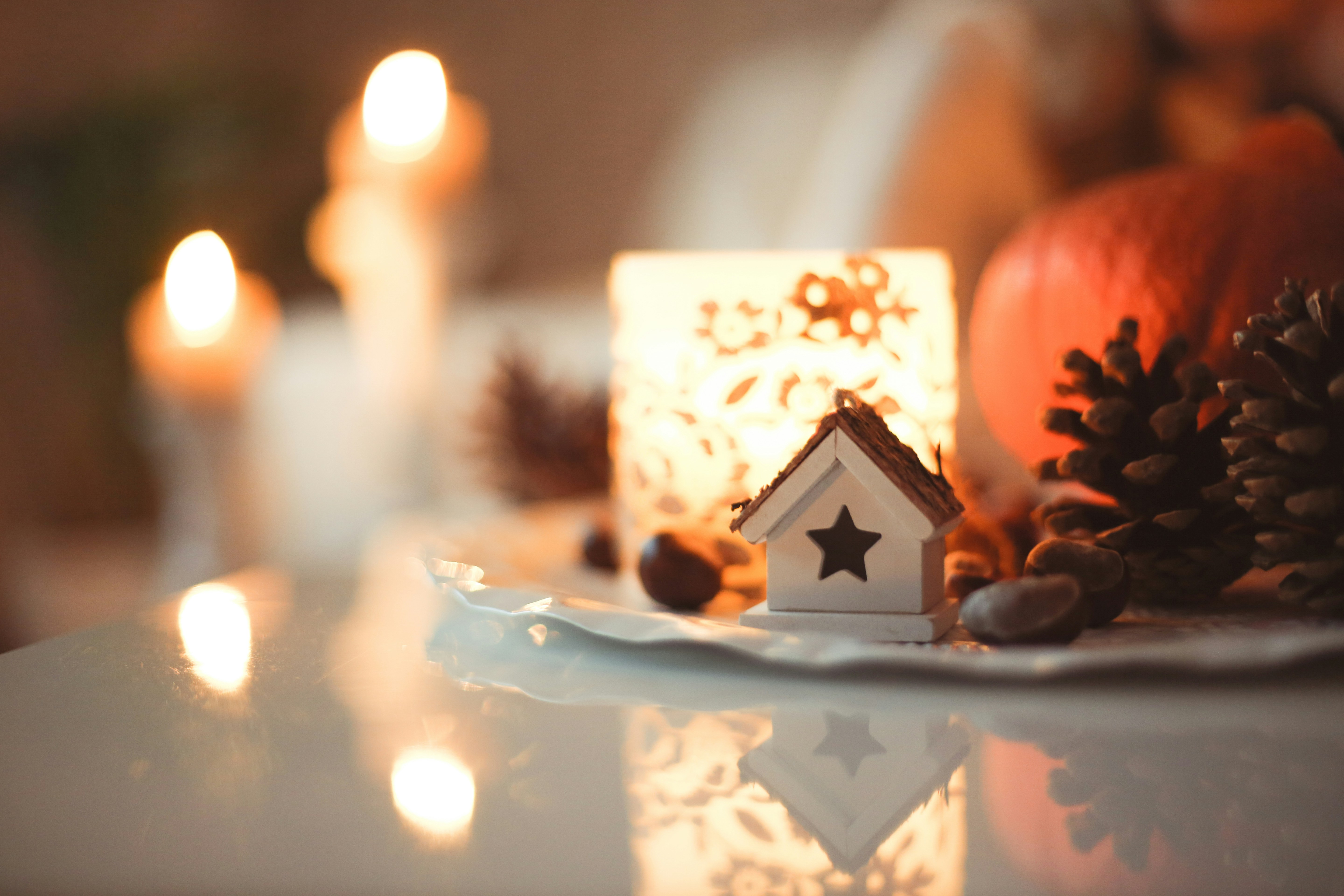 A candle, some chesnuts and a decorative house on a plate