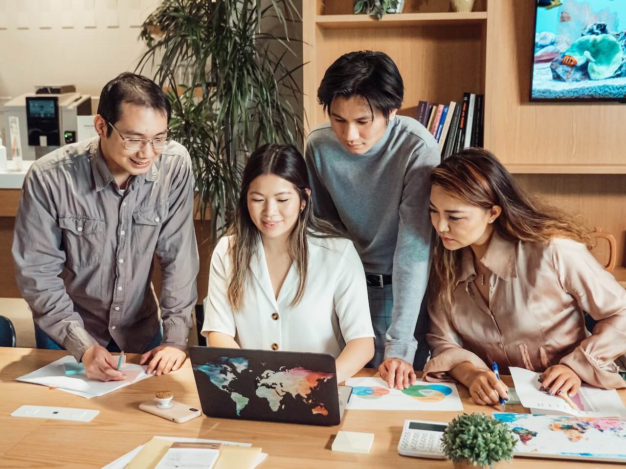 A virtual assistant team gathers around a laptop in the office