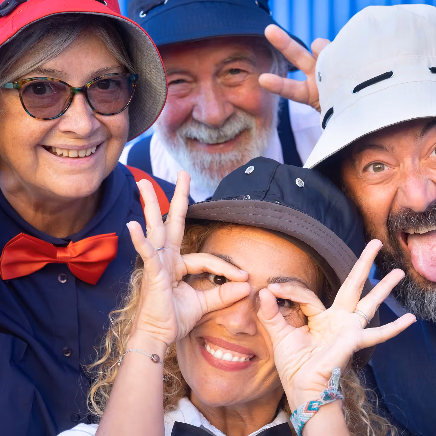 Four friends in hats laughing and making silly faces at a photo booth