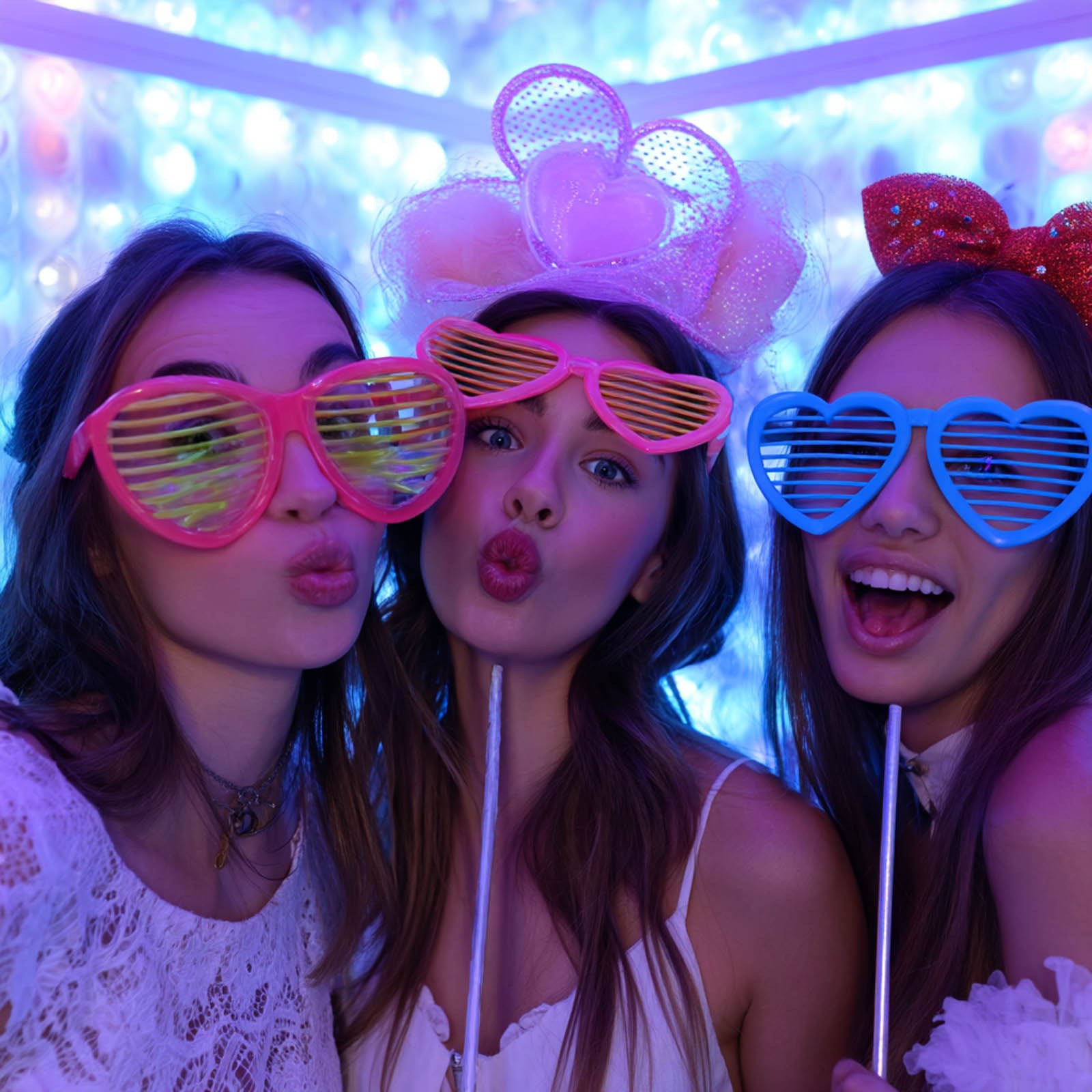 Friends posing with props in a colorful photo booth