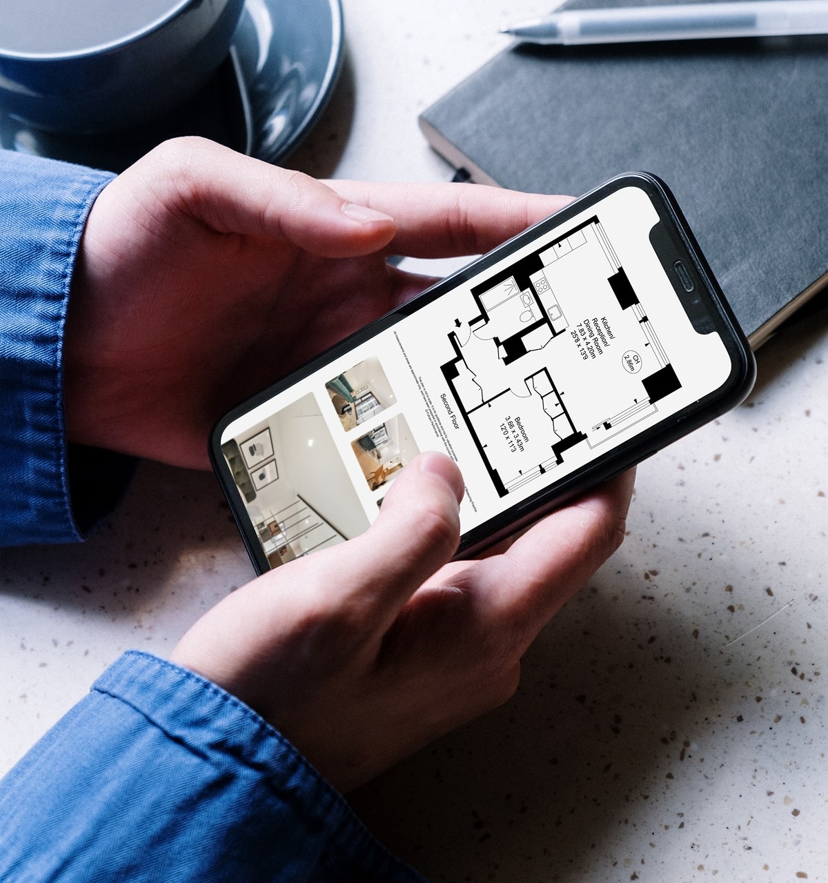 Close up of hands holding a mobile phone showing floor plans on the screen