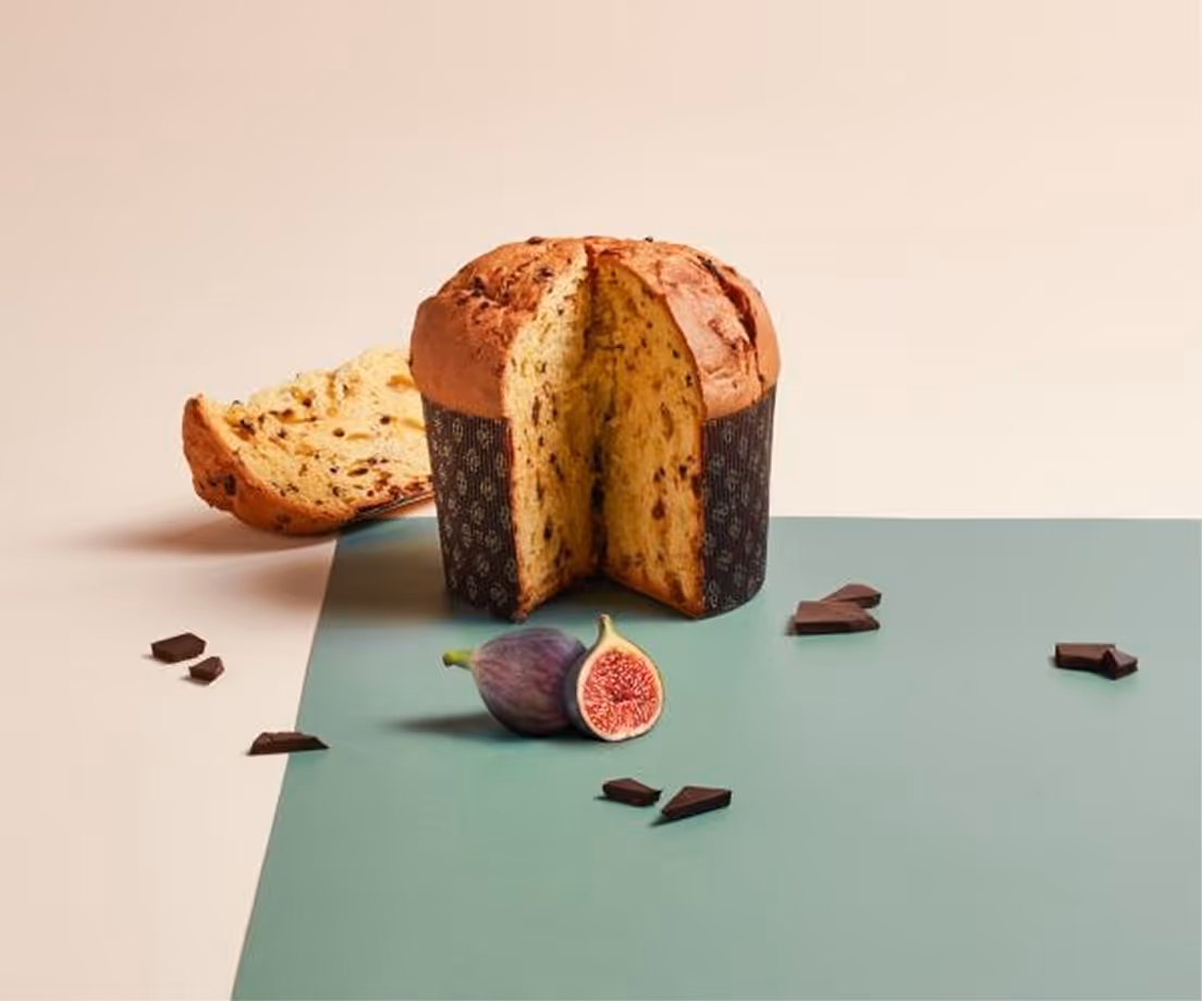 Panettone artigianale al cioccolato con fichi freschi affettati e pezzi di cioccolato sparsi.