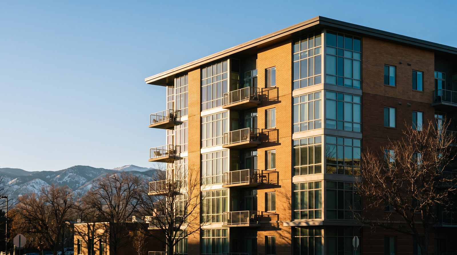 Modern mid-rise condominium building in Denver with the Front Range foothills behind it
