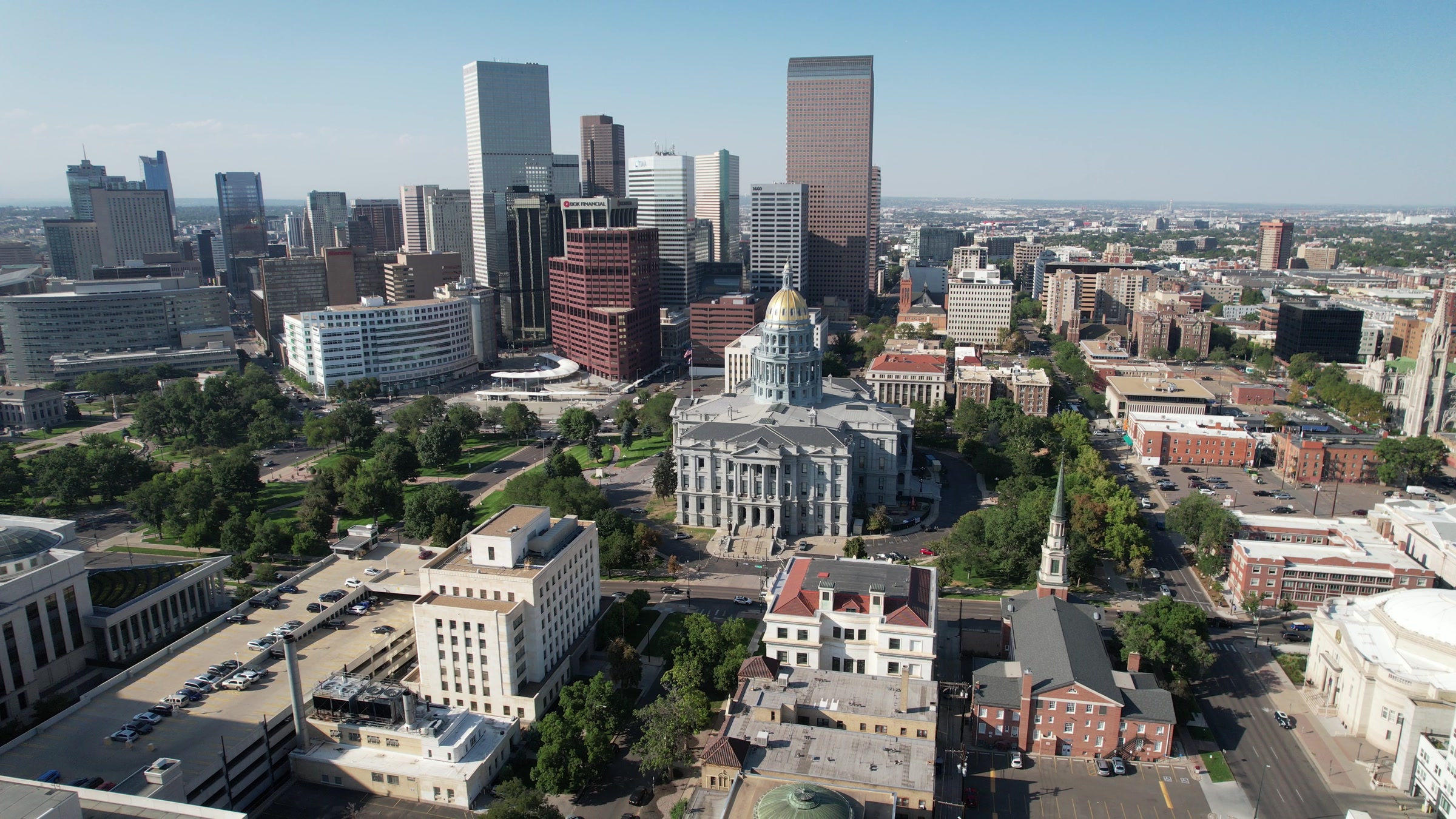Aerial view of the Colorado State Capitol's gold dome with downtown Denver's skyline behind it