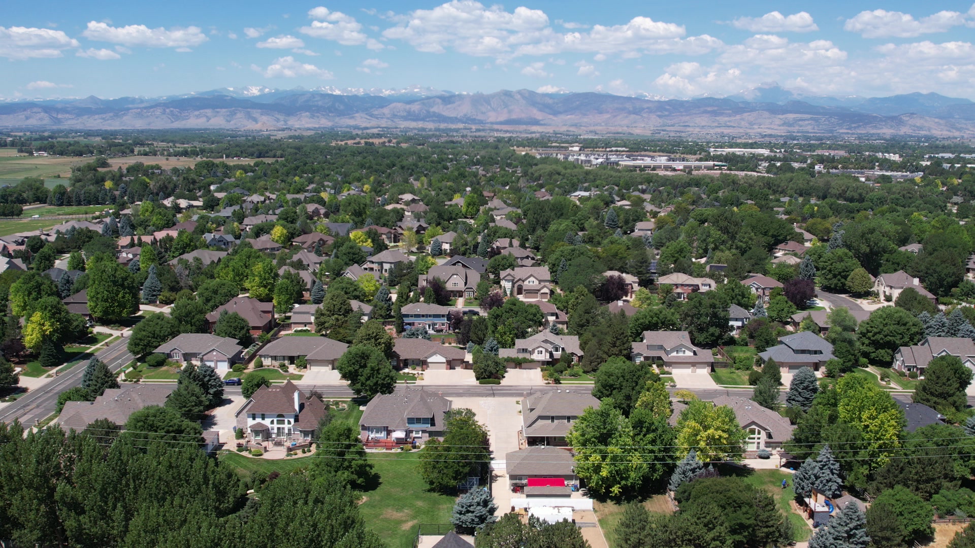 Tree-lined Longmont neighborhoods with the Front Range under big clouds