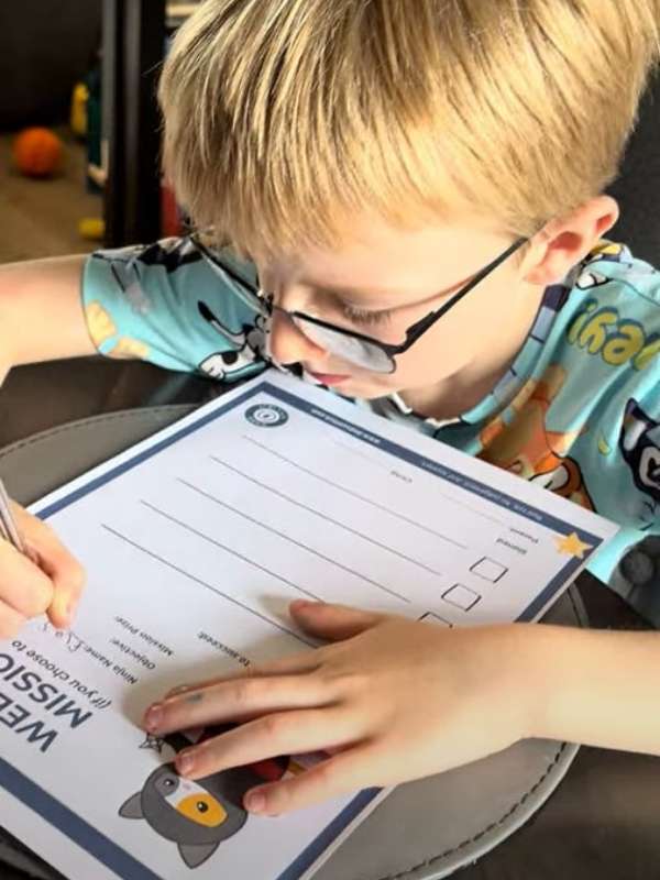 An ADHD boy writing his ADHD weekend ninja missions on the sheet