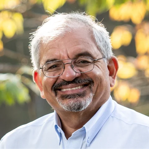 A man with a white beard and glasses smiling for the camera.
