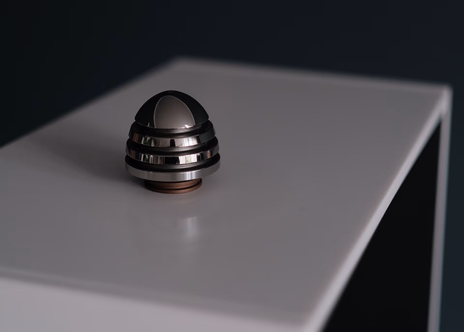 A small, shiny, dome-shaped structure on a white surface - a phiton resonator.