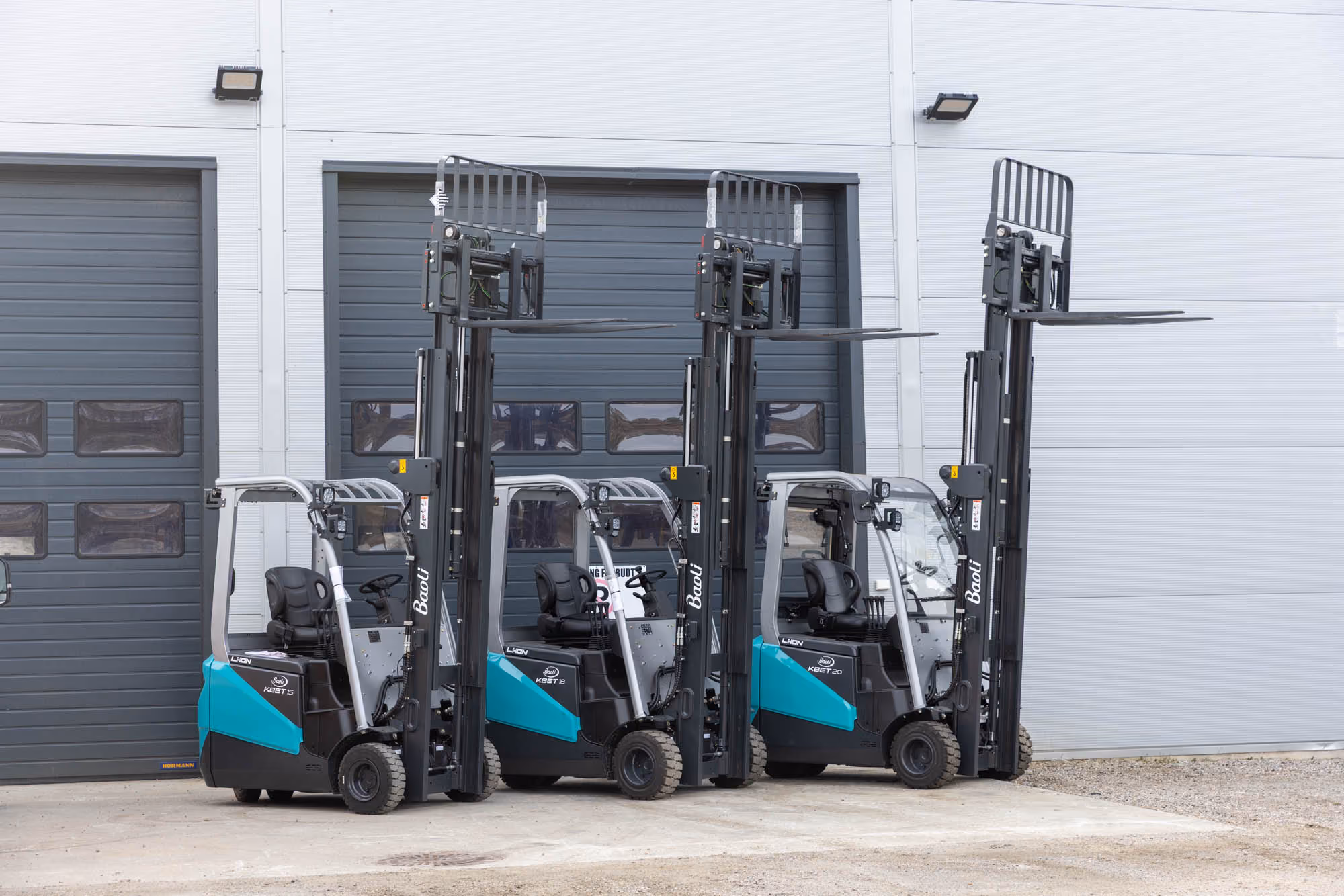Blå og hvit Baoli gaffeltruck parkert inne i en stor industribygning.
