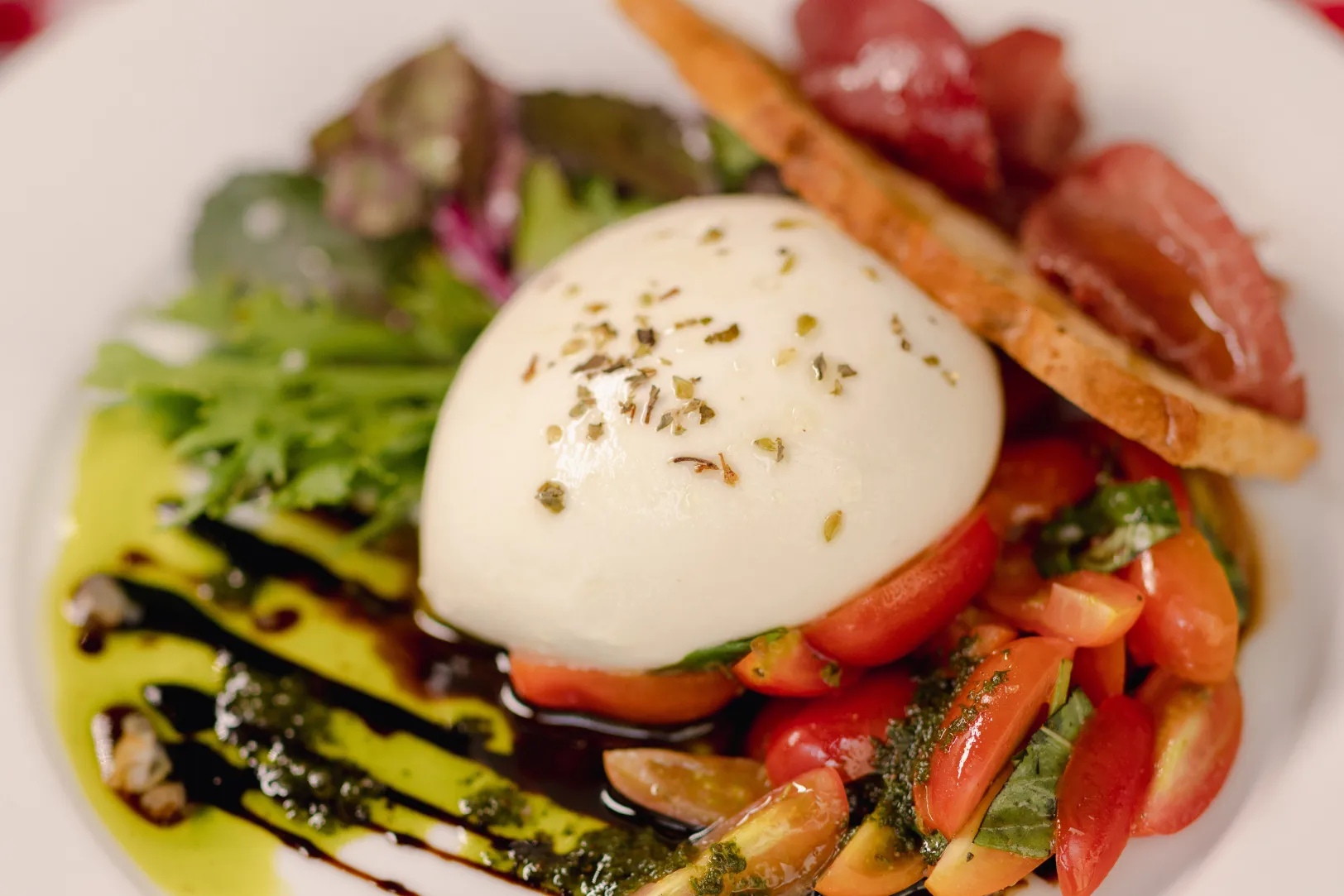 Close-up of a gourmet Caprese salad with burrata, cherry tomatoes, pesto, and balsamic glaze, suggesting local dining experiences near Liberty at Estrella Falls in Goodyear, AZ.