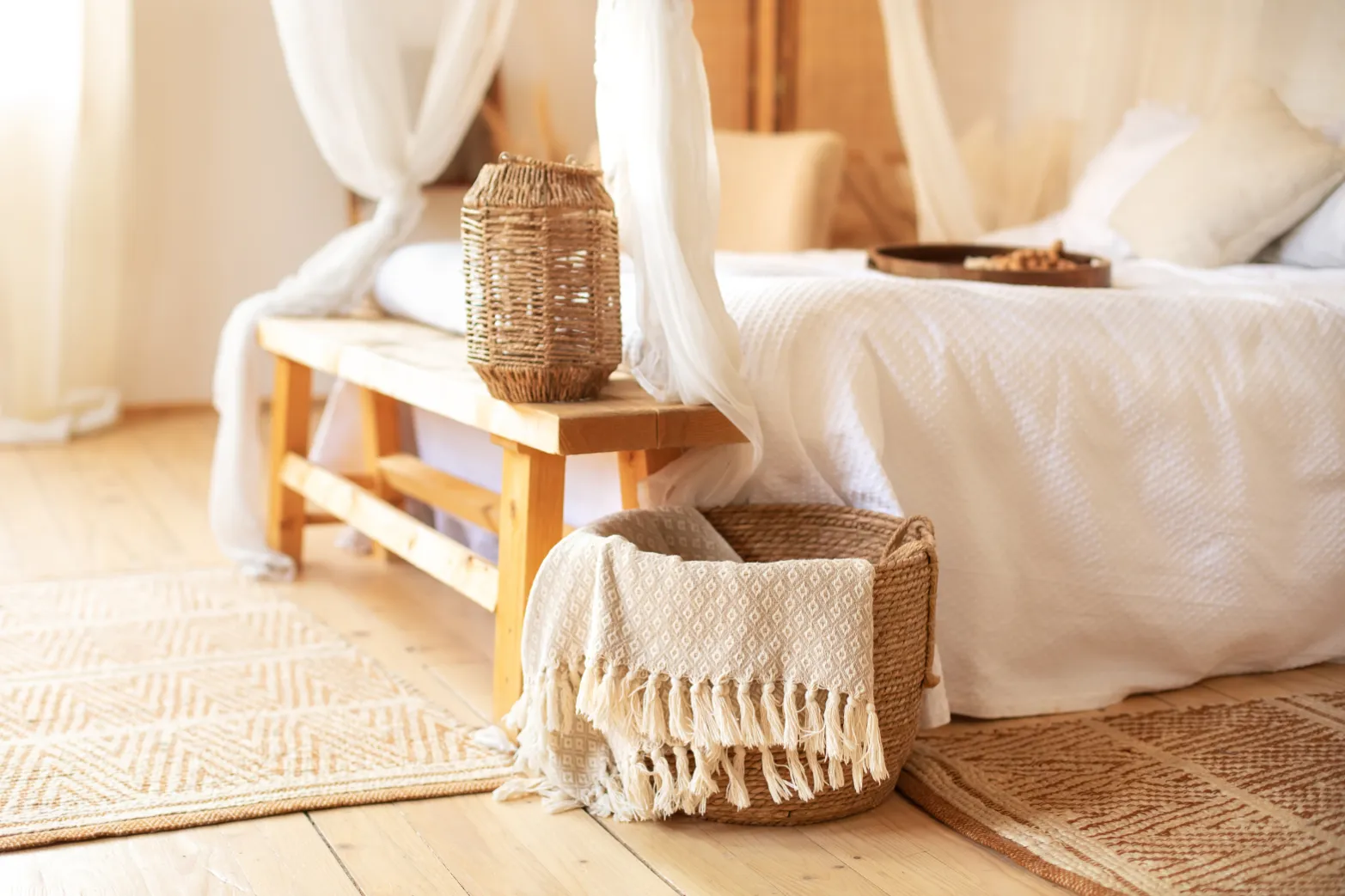 Bright bedroom interior with a white bed, decorative bench, and woven basket, showcasing comfortable living at Liberty at Estrella Falls in Goodyear, AZ.