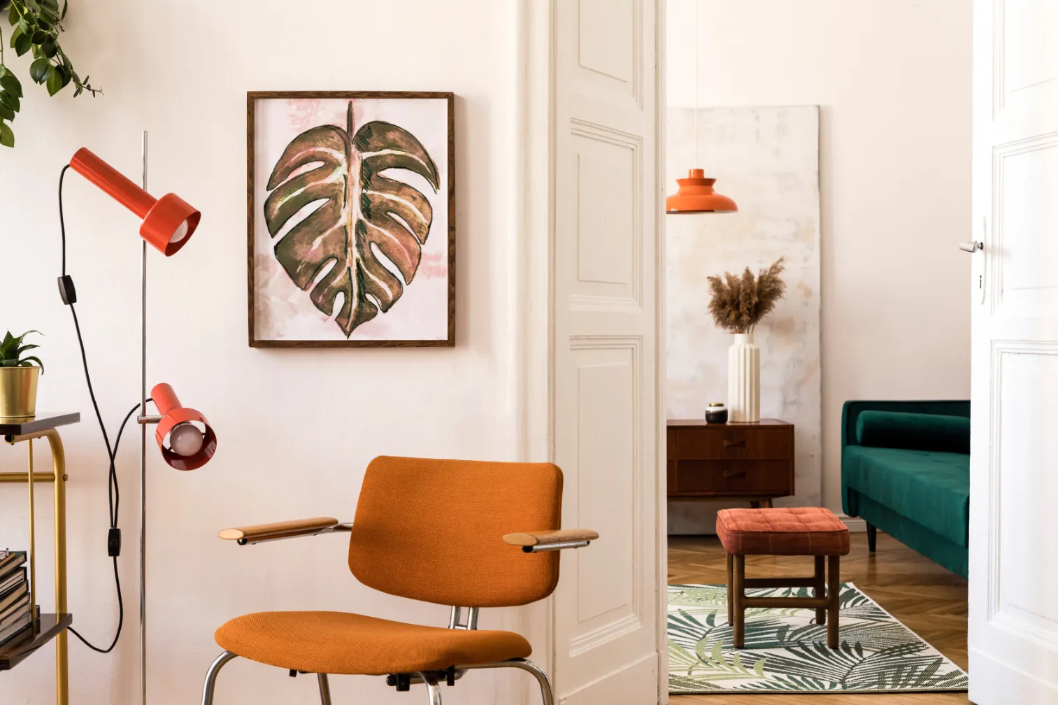 Vibrant living area with an orange armchair, unique floor lamp, and monstera leaf artwork, highlighting the modern and artistic interiors at Liberty at Estrella Falls in Goodyear, AZ.