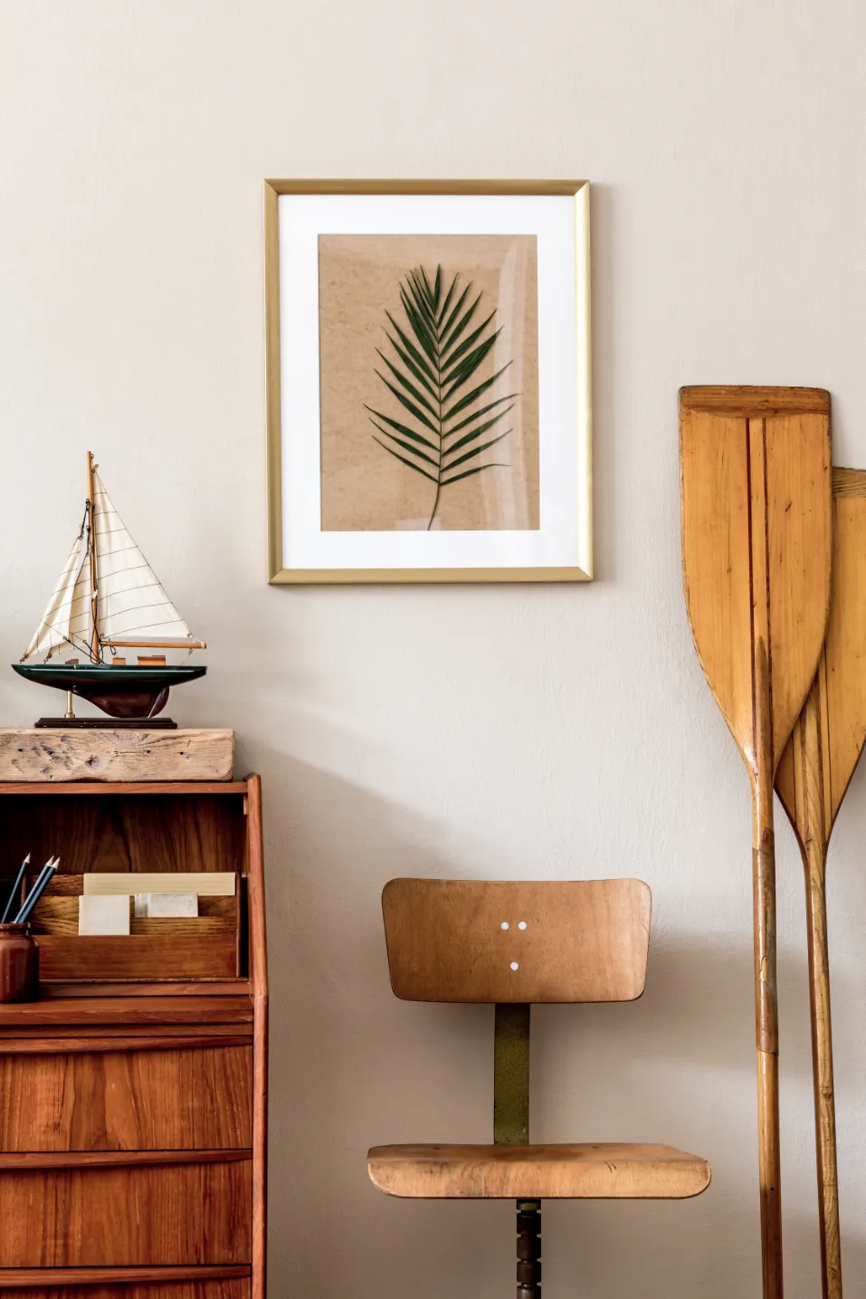 Stylish office or study nook with a wooden desk, sailboat model, framed plant art, and decorative paddles, reflecting the unique interiors at Liberty at Estrella Falls in Goodyear, AZ.